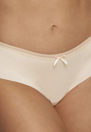 Slips in cotone beige con un delicato bordo in pizzo e un piccolo fiocco in satin al centro davanti, caratterizzati da una texture liscia e un design aderente.