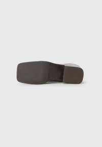 Semelle de chaussure marron avec une finition lisse, dotée d'un talon rectangulaire et d'une texture subtile. L'arrière-plan est blanc uni.