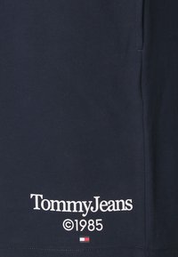 Navy blue cotton t-shirt featuring "Tommy Jeans" logo in white text, with ©1985 and a small red, white, and blue flag accent.