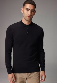 Camisa polo negra de manga larga con cuello acanalado, tapeta de tres botones y puños ajustados, hecha de un material de punto suave.