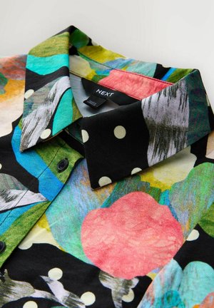 Värvikas nööpidega särk, millel on abstraktsete kujundite ja täppide kombinatsioon. Valmistatud tekstuurse pinnaga kangast. Kaubamärgi silt on nähtav.