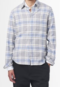 Lehké kostkované košile v odstínech šedé, modré a bílé. Vyrobené z měkké látky, s knoflíkovým zapínáním na přední straně a dlouhými rukávy.