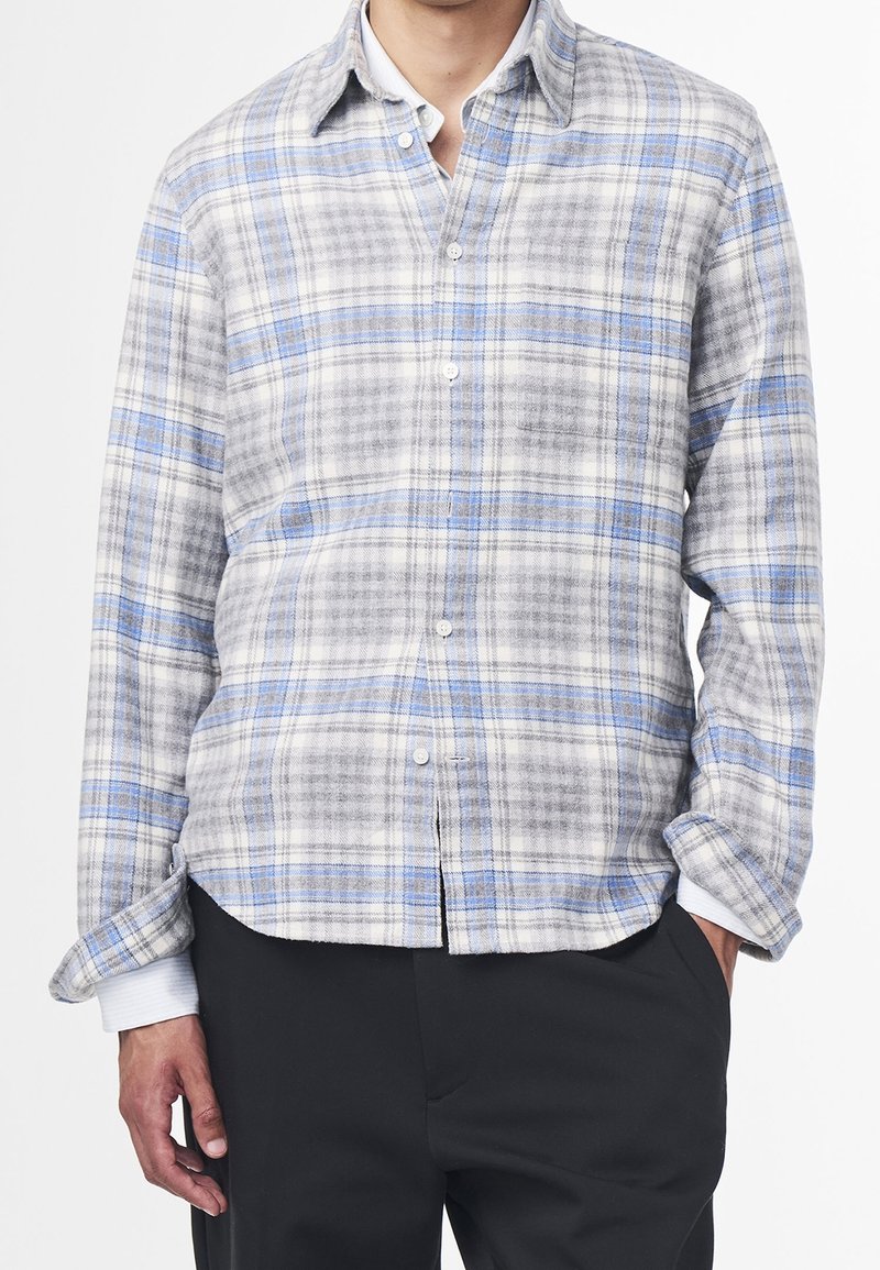 Lehké kostkované košile v odstínech šedé, modré a bílé. Vyrobené z měkké látky, s knoflíkovým zapínáním na přední straně a dlouhými rukávy.