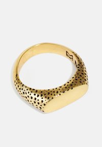 Goldfarbener Ring mit einer glatten Oberfläche und einem strukturierten Band, das kleine schwarze Punkte zeigt. Der Ring hat ein modernes, breites Design.