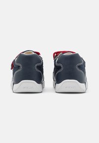 Sneakers in pelle e mesh blu navy con dettagli rossi, fascia in Velcro e suola in gomma bianca, caratterizzati da un retro testurizzato con dettaglio del logo.