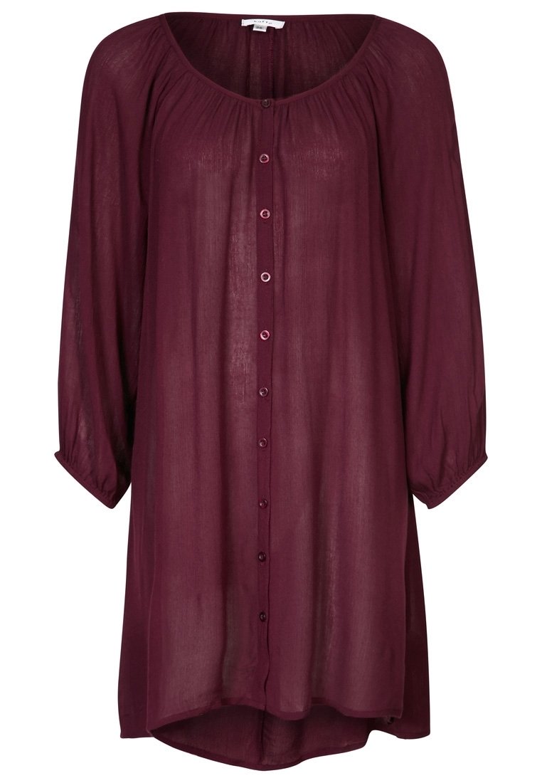 Chemise bordeaux à manches longues en tissu transparent. Elle présente un col rond, une fermeture à boutons sur le devant et un ourlet arrondi.