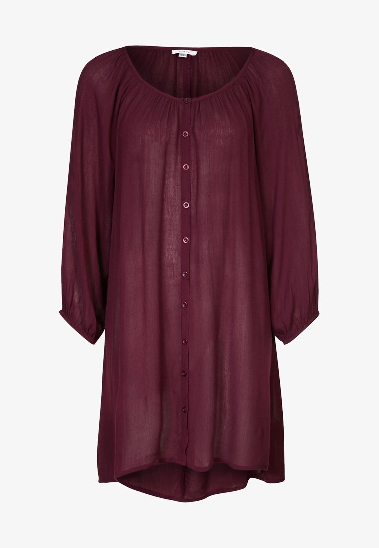 Chemise bordeaux à manches longues en tissu transparent. Elle présente un col rond, une fermeture à boutons sur le devant et un ourlet arrondi.