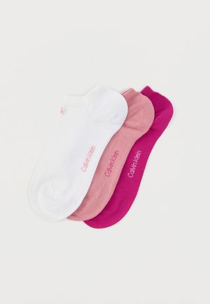 Trois paires de socquettes : une blanche, une rose clair et une rose foncé, chacune avec un logo « Calvin Klein » en couleurs contrastantes.