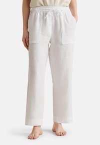 Pantalones de lino blancos con corte holgado, que cuentan con una cinturilla elástica, cordón y dos bolsillos frontales grandes. Textura suave, diseño de pierna recta.
