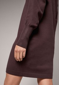 Bordowa dzianinowa sukienka z długimi rękawami, wykończeniem na ściągaczach i prostym dołem. Tkanina ma gładką fakturę i dopasowany krój.