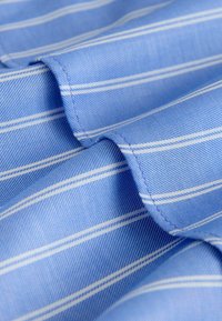 Light blue fabric with vertical white stripes, featuring a smooth texture and crisp finish. Visible stitching detail along edges.