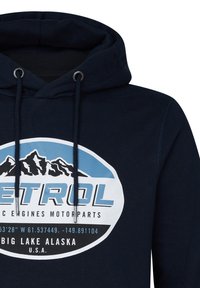 Sudadera azul marino con cordones ajustables, que presenta un gráfico circular con montañas, la palabra "PETROL" y detalles de ubicación.