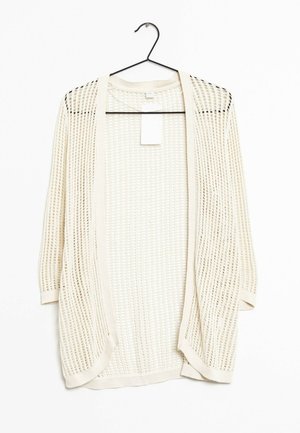 Cardigan au crochet couleur crème à ouverture frontale avec manches trois-quarts suspendu sur un cintre noir sur fond blanc.
