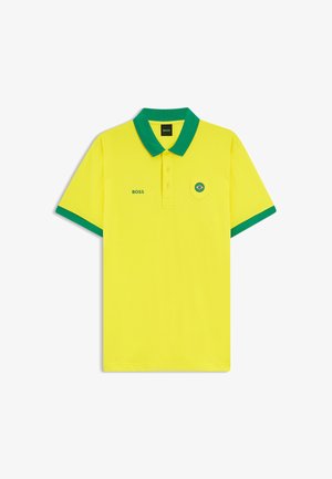 Gul polo-shirt med grøn krave og ærmekanter, "BOSS"-logo på brystet og et lille brasiliansk flag på lommen.