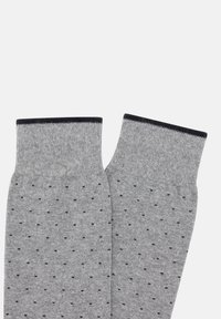 Šedé ponožky s texturovanou tkaninou, zdobené vzorem malých černých teček a tmavými žebrovanými manžetami na vrcholu.