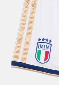 White sports jersey with gold satin stripes, featuring an embroidered blue, green, and red Italy crest with four stars above.