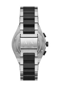 Stalowa bransoleta z czarnymi ogniwami zegarka z wygrawerowanym logo Armani Exchange na zapięciu, zegarek częściowo widoczny z tyłu.