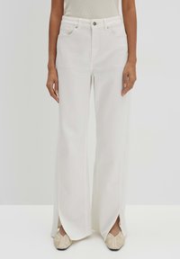 White wide-leg jeans made of denim, featuring a high waist, front pockets, and side slits at the hem for added detail.