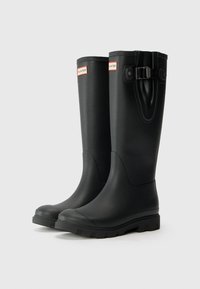 Bottes de pluie en caoutchouc noires avec un bout arrondi, une semelle texturée et un détail de sangle réglable en haut. Fini lisse avec un logo en relief.