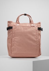 Sac fourre-tout en tissu rose avec double poignée, poche avant et sangle réglable. Présente une texture lisse et un design simple, étiqueté "anello".