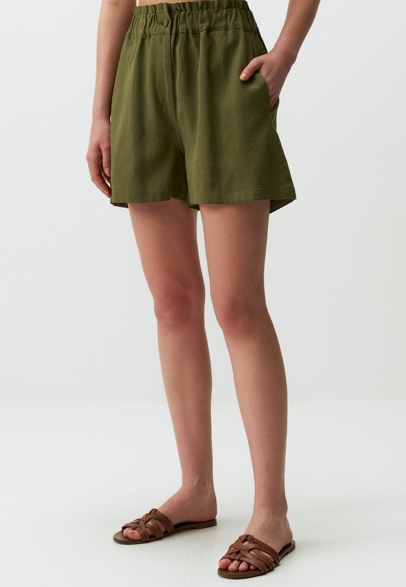 Olivgrüne Shorts mit lässiger Passform, elastischem Bund und Seitentaschen. Das Material scheint leicht und hat eine leicht strukturierte Oberfläche.