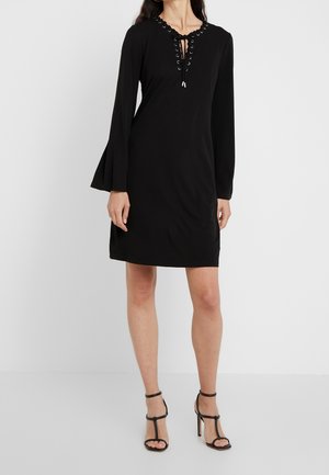 Schwarzes Kleid mit langen Glockenärmeln, V-Ausschnitt mit Stoffschnürung und Metallösen. Glatte Textur, knielanges Design.