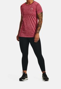 Red heathered athletic t-shirt with short sleeves, featuring a small logo and black leggings paired with black athletic shoes.