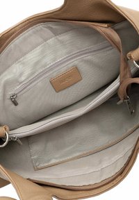 Tan leather handbag interior with light gray lining. Features include one zip pocket, a slip pocket, and a debossed label marked "RUE 09."