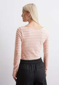 Long-sleeve top in soft, lightweight fabric featuring pink and white horizontal stripes. Rounded neckline and fitted sleeves. Pair of black, elastic-waist pants.