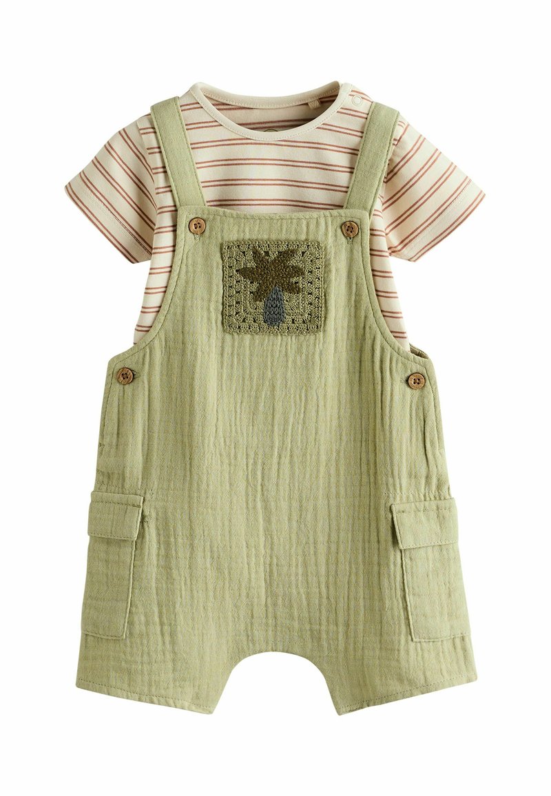 Gröna texturerade overaller med en palmträdapplikation, i kombination med en beige randig t-shirt. Har knappdetaljer och sidofickor.