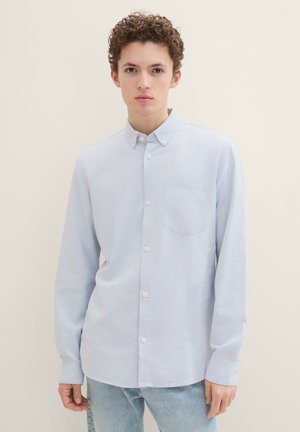 Hellblaues Hemd mit langen Ärmeln, Kragen und einer Brusttasche. Hergestellt aus einem weichen, strukturierten Stoff. Weiße Knöpfe betonen das Design.
