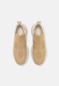 Beige Strick-Slipper mit strukturiertem Obermaterial, runder Zehenpartie und einer weißen Gummisohle sowie Akzenten. Mit einer Lasche an der Ferse.
