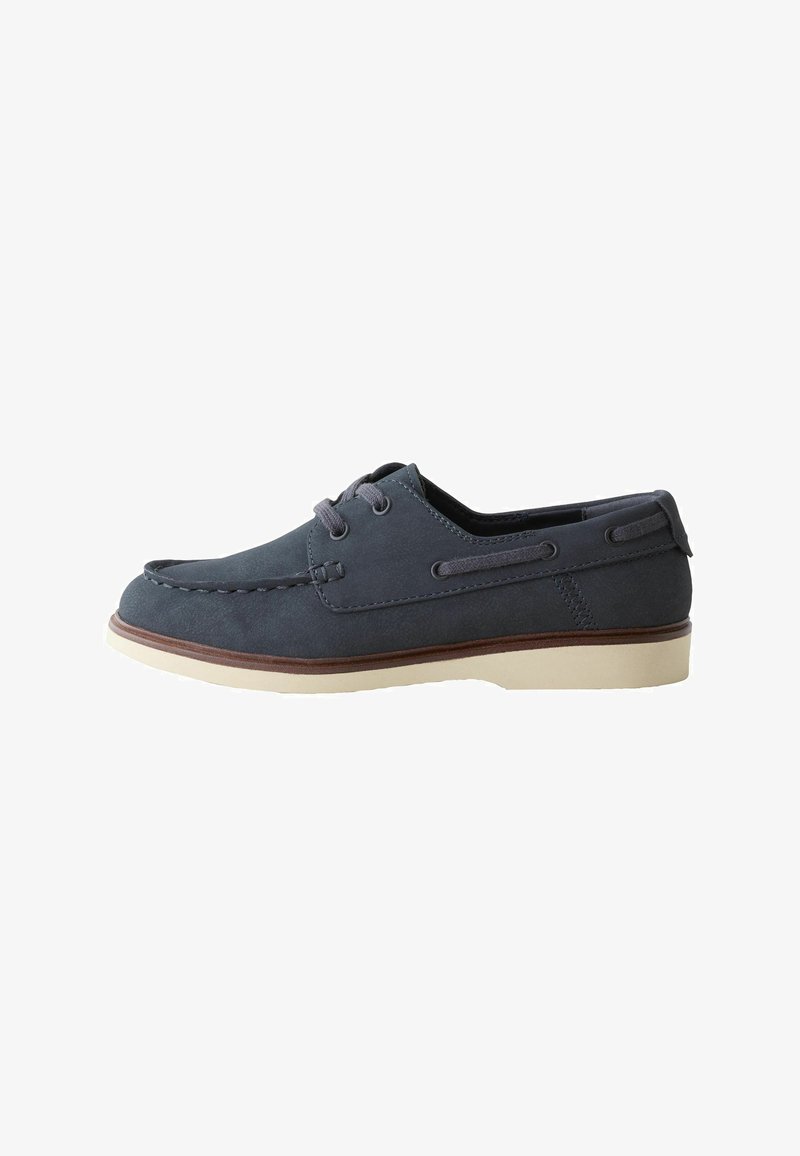 Chaussure bateau décontractée bleu foncé avec semelle blanche, lacets à l’avant, couture moc toe et un détail en cuir autour du talon et des côtés.