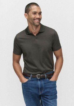 Ciemnozielona koszulka polo z kołnierzykiem, z krótkimi rękawami, zestawiona z niebieskimi dżinsami i brązowym plecionym paskiem. Prosty i casualowy design.