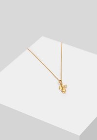 Collana d'oro con una catena delicata e un piccolo ciondolo di angelo che tiene un cuore, con superfici lisce e forme arrotondate.