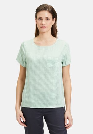 Mintgroene top met korte mouwen en een ronde hals, voorzien van een subtiel geometrisch patroon en een klein borstzakje. Zacht, lichtgewicht materiaal.