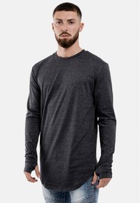 Langsleeve, donkergrijze t-shirt gemaakt van zacht stof. Heeft een ronde halslijn en een verlengd achterdeel. Casual pasvorm, met aansluitende mouwen.