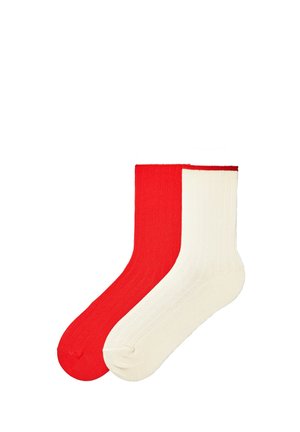 Deux chaussettes côtelées, une rouge unie et une blanc cassé unie, placées en chevauchement sur un fond blanc.
