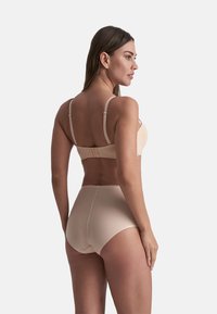 Beige Dessous-Set mit einem nahtlosen BH mit verstellbaren Trägern und hochgeschnittenen Unterhosen. Glattes Material und minimaler Hardwareeinsatz.