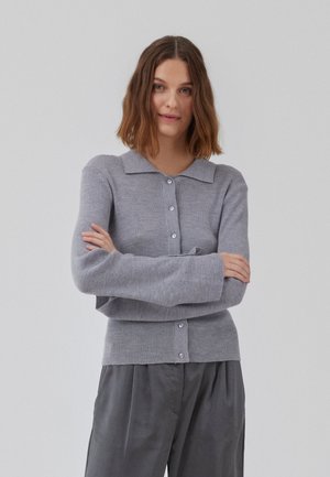 Grå ribbestrikket cardigan med krage, med lange ermer og knappedrag, kombinert med løse grå bukser.