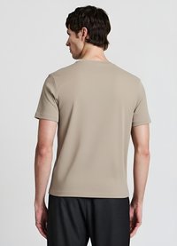 T-shirt beige a maniche corte con una texture liscia, colletto rotondo e design minimalista, vista da dietro. Nessun logo o motivo visibile.