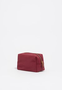 Bolsa de cosméticos rectangular roja, hecha de tela suave, con un cierre dorado en la parte superior y un pequeño lazo para facilitar el transporte.