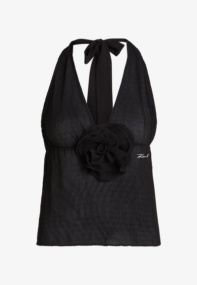 Haut noir sans manches style dos-nu avec tissu texturé, grande décoration fleur en tissu à la taille et fermeture à nouer au cou.