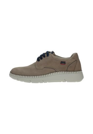 Zapato de ante beige con punta redonda, cordones azul oscuro y suela de goma blanca. Costuras cuidadas alrededor de los bordes y un pequeño logo en el lateral.