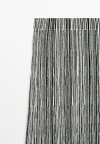 Jupe en tissu plissé à rayures noires et blanches, présentant une surface texturée avec des épaisseurs variées et une taille lisse en haut.