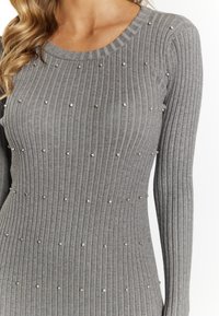 Maglione grigio a costine con maniche lunghe e scollatura rotonda, impreziosito da borchie metalliche per un dettaglio testurizzato.
