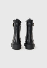 Black leather ankle boots with a smooth texture, featuring a zipper closure, side straps, and a low block heel.
