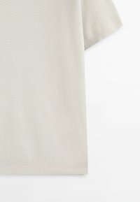 T-shirt court à manches courtes texturé gris clair avec un motif en nid d'abeille et un ourlet côtelé. Tissu doux avec une coupe décontractée.
