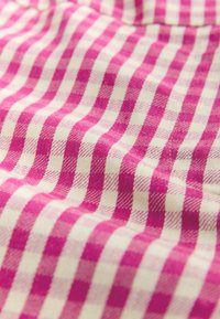 Tissu à carreaux rose et crème avec une texture tissée. Présente des carrés alternés, audacieux et subtils, affichant un motif vichy classique.