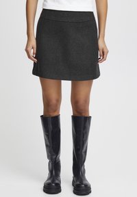 Grå ull mini kjol med en åtsittande midjeband, subtila sömdetaljer, parat med knähöga svarta läderstövlar.